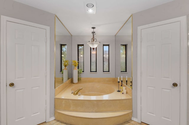 bathroom with a tub to relax in and a healthy amount of sunlight