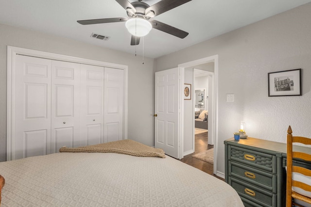 bedroom with ceiling fan, dark wood-type flooring, and a closet