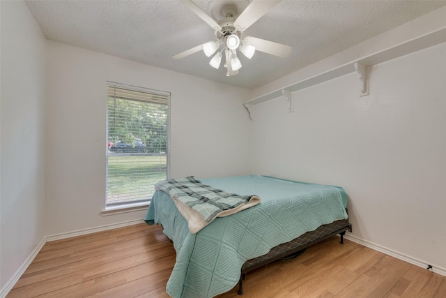 bedroom with a textured ceiling, light wood-type flooring, and ceiling fan