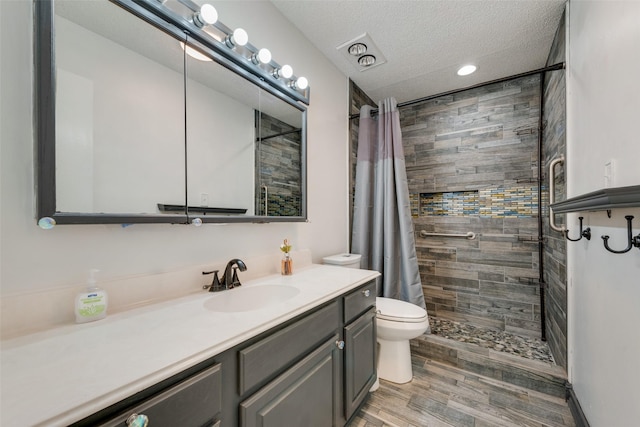 bathroom featuring vanity, a textured ceiling, toilet, and walk in shower