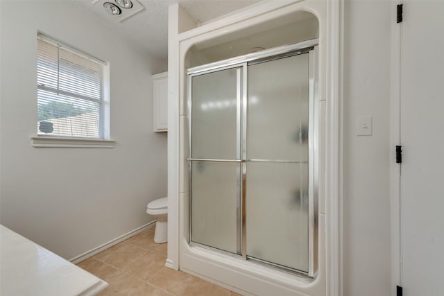 bathroom featuring a shower with shower door, tile patterned floors, toilet, and a textured ceiling