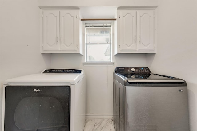 clothes washing area with washer and clothes dryer and cabinets