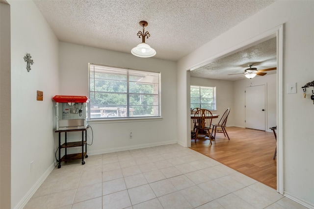 tiled dining space with ceiling fan and a textured ceiling