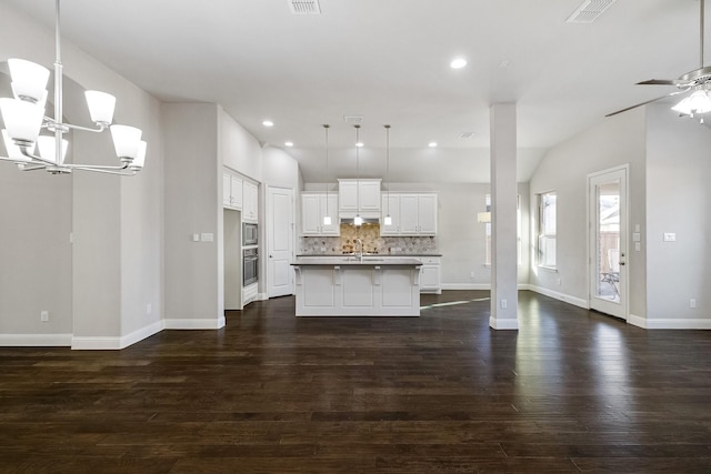 kitchen with a center island with sink, a kitchen breakfast bar, white cabinets, decorative backsplash, and appliances with stainless steel finishes