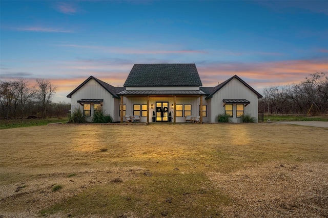 back house at dusk featuring a yard and french doors