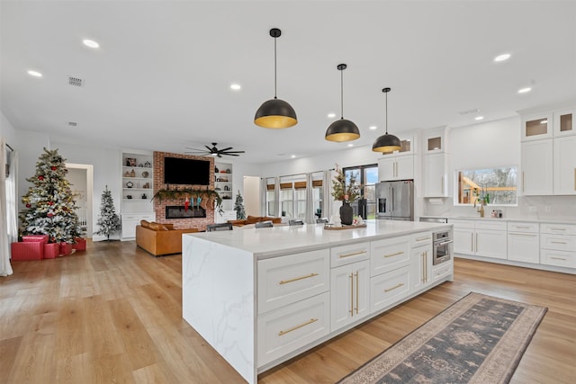 kitchen featuring white cabinets, appliances with stainless steel finishes, a center island, and pendant lighting