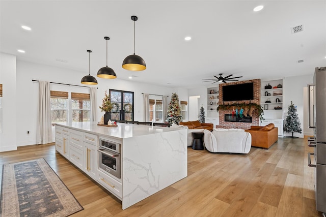 kitchen featuring built in shelves, white cabinetry, stainless steel oven, pendant lighting, and a kitchen island