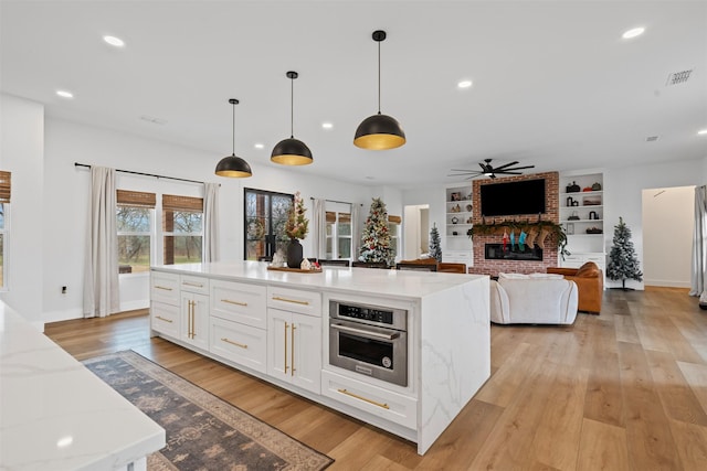 kitchen featuring white cabinets, hanging light fixtures, light stone countertops, built in features, and appliances with stainless steel finishes