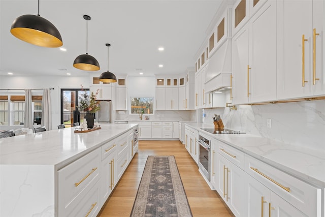 kitchen with tasteful backsplash, stainless steel appliances, a spacious island, pendant lighting, and white cabinets