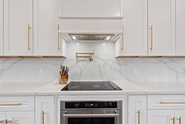 kitchen with white cabinetry, decorative backsplash, stainless steel oven, and light stone countertops