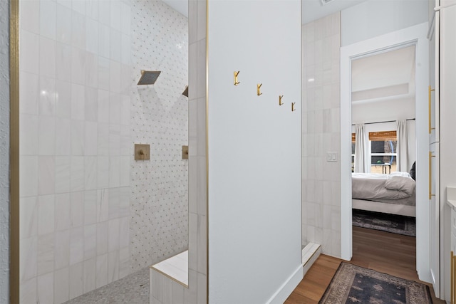 bathroom with a tile shower and wood-type flooring