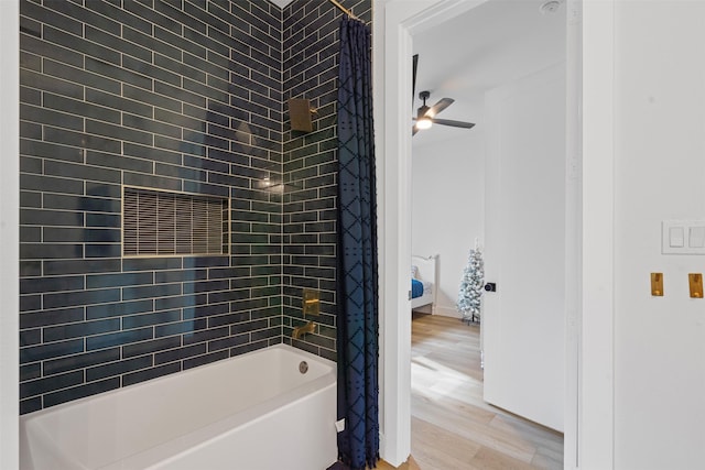 bathroom with tiled shower / bath combo, ceiling fan, and wood-type flooring