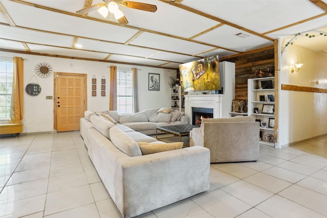 living room with plenty of natural light, wood walls, light tile patterned floors, and ceiling fan