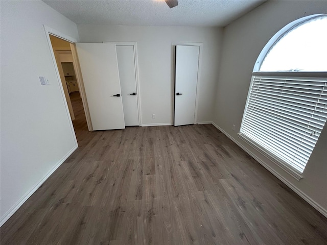 unfurnished bedroom with a textured ceiling, hardwood / wood-style flooring, and ceiling fan