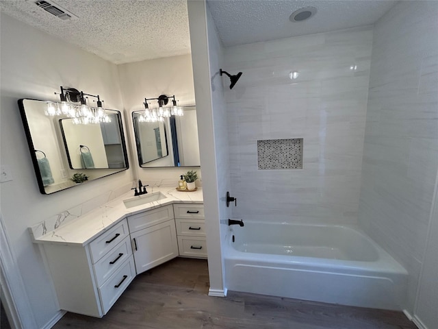 bathroom featuring tiled shower / bath, vanity, hardwood / wood-style floors, and a textured ceiling