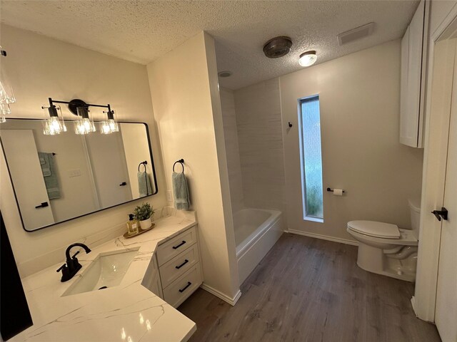 bathroom featuring hardwood / wood-style floors, vanity, a textured ceiling, and toilet