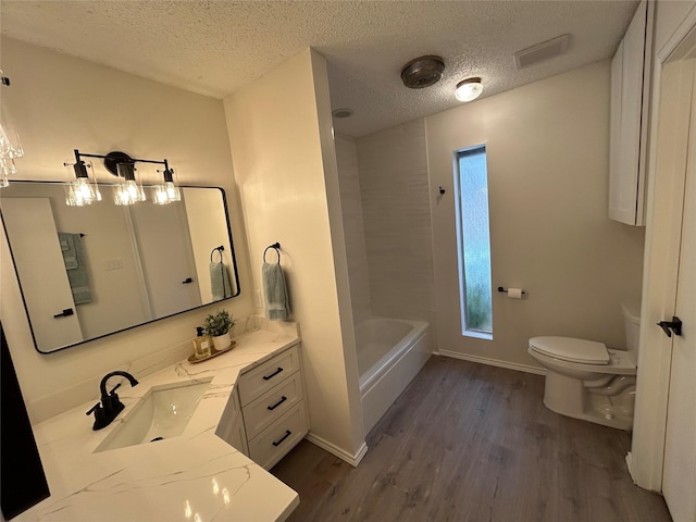 bathroom featuring a washtub, hardwood / wood-style floors, vanity, a textured ceiling, and toilet