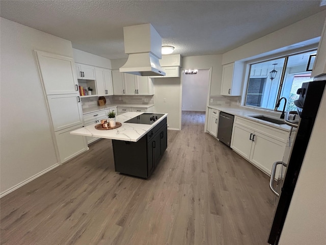 kitchen with a kitchen island, sink, white cabinets, black appliances, and light hardwood / wood-style flooring