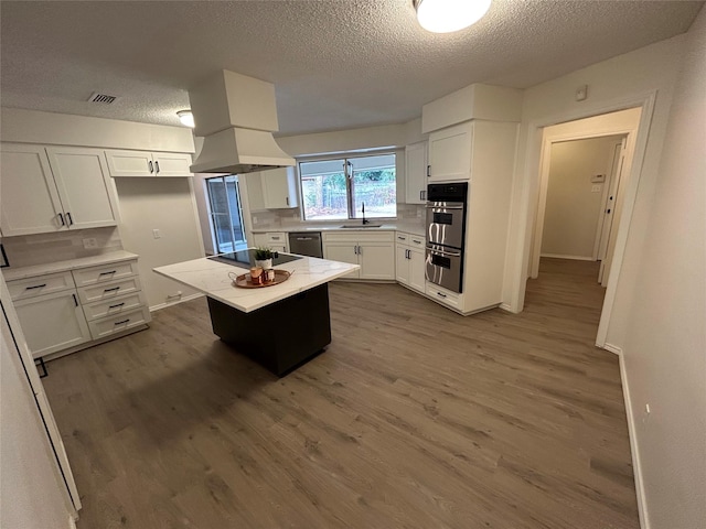 kitchen with sink, white cabinetry, wood-type flooring, a center island, and stainless steel appliances