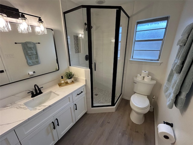 bathroom with hardwood / wood-style floors, vanity, a shower with shower door, and toilet