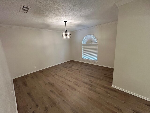 spare room with ornamental molding, a textured ceiling, dark wood-type flooring, and a notable chandelier