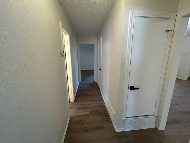 corridor featuring dark hardwood / wood-style flooring and a textured ceiling