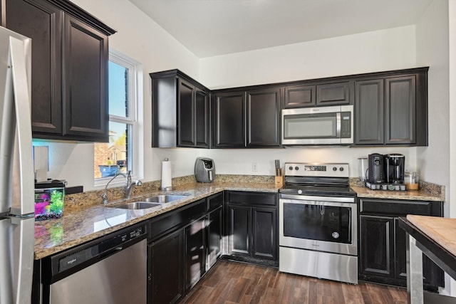 kitchen with light stone countertops, dark hardwood / wood-style flooring, stainless steel appliances, and sink