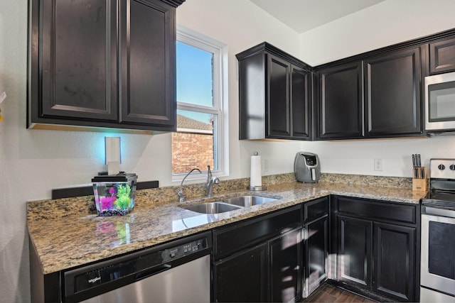 kitchen with light stone counters, sink, dark wood-type flooring, and appliances with stainless steel finishes