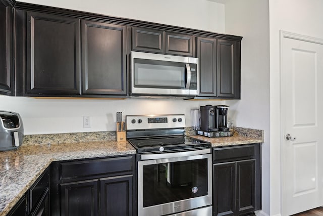 kitchen with light stone counters and appliances with stainless steel finishes