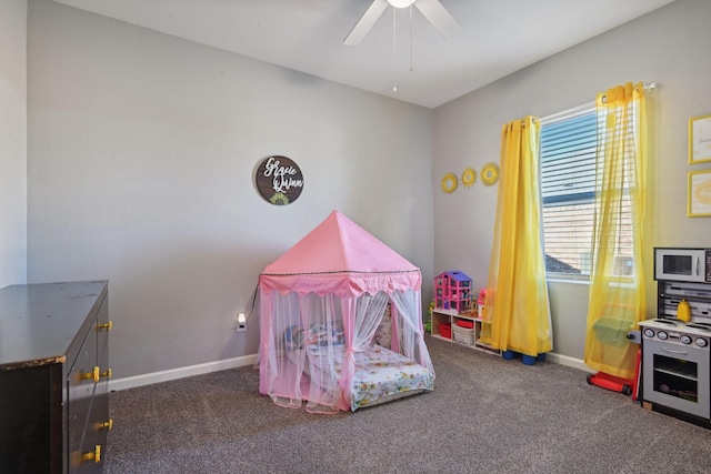 playroom with ceiling fan and dark colored carpet