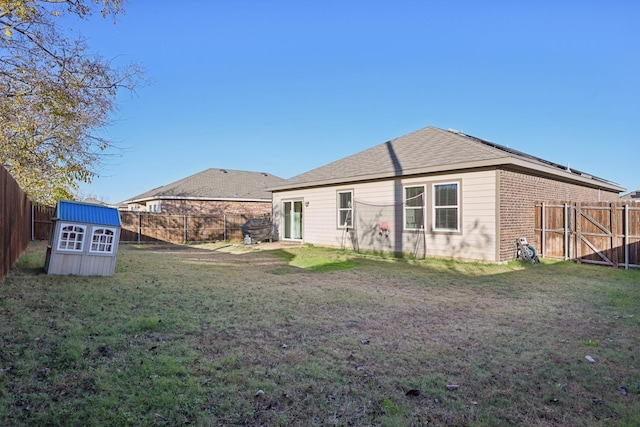 back of property featuring a lawn and a storage shed