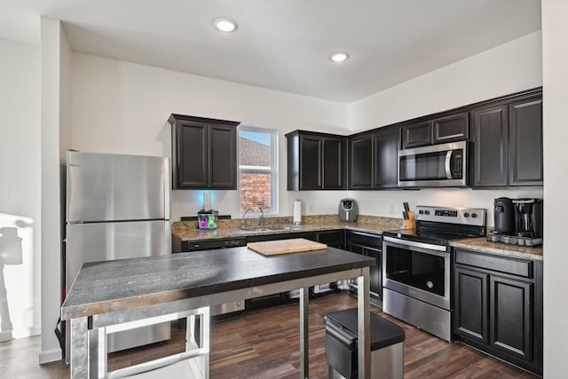 kitchen featuring sink, dark hardwood / wood-style flooring, light stone counters, and appliances with stainless steel finishes