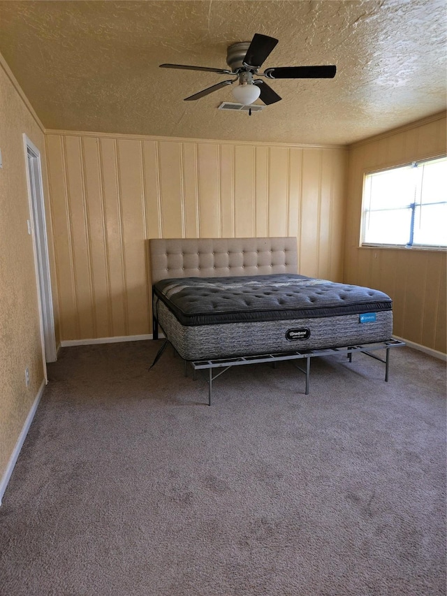 carpeted bedroom featuring ceiling fan and a textured ceiling