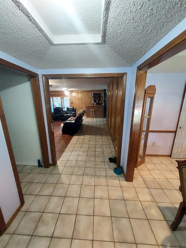 hallway featuring a textured ceiling and light tile patterned flooring