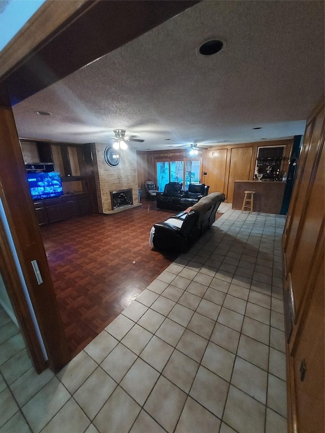 unfurnished living room with ceiling fan, a large fireplace, parquet floors, and a textured ceiling