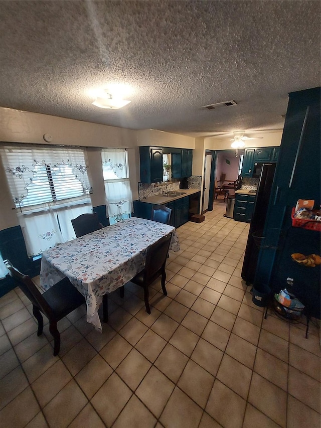 tiled dining room with a textured ceiling, ceiling fan, and sink