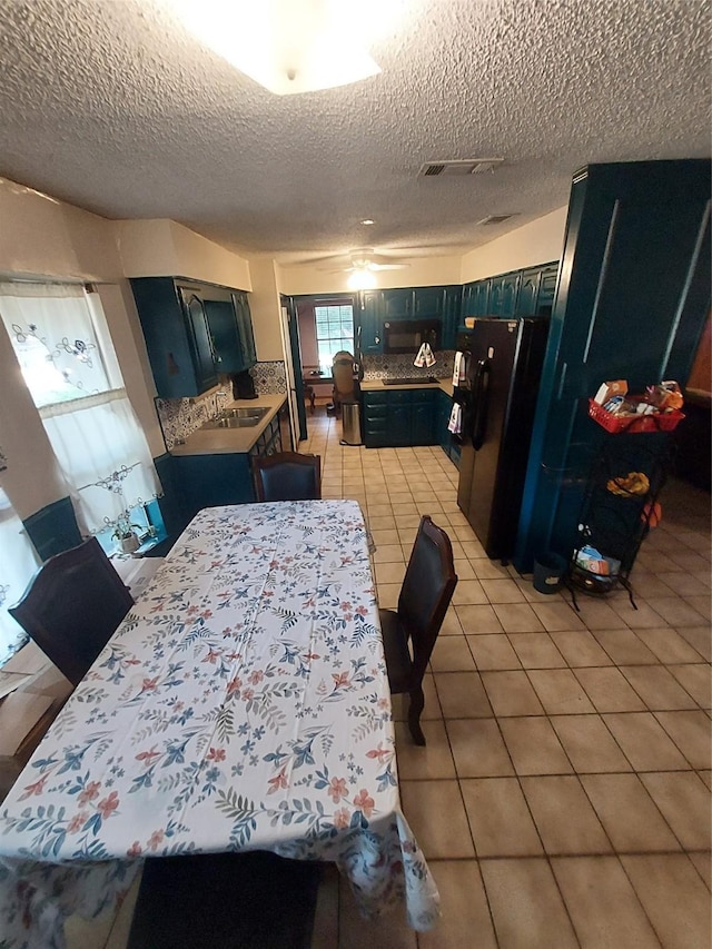 kitchen featuring black appliances, sink, light tile patterned floors, and a textured ceiling