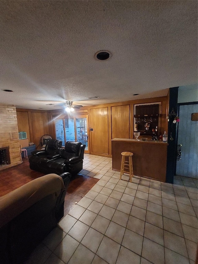 tiled living room featuring wood walls and a fireplace