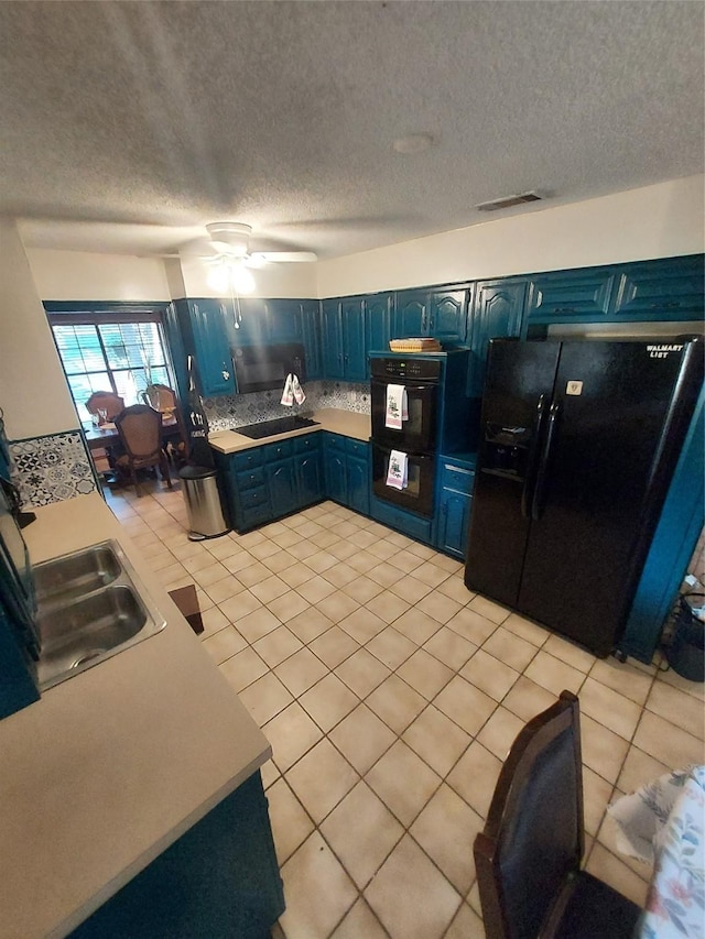 kitchen with black appliances, sink, ceiling fan, light tile patterned floors, and blue cabinetry