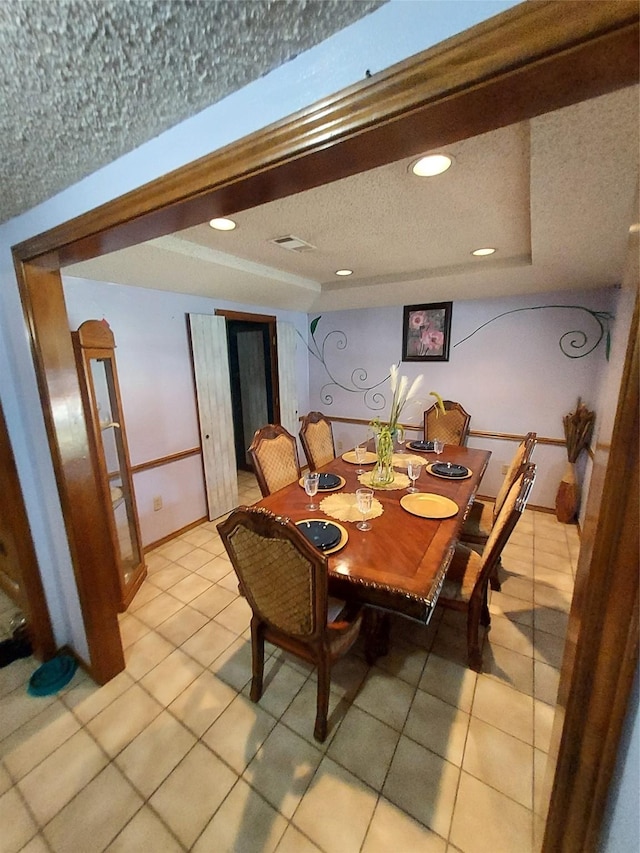 dining space featuring light tile patterned floors and a tray ceiling