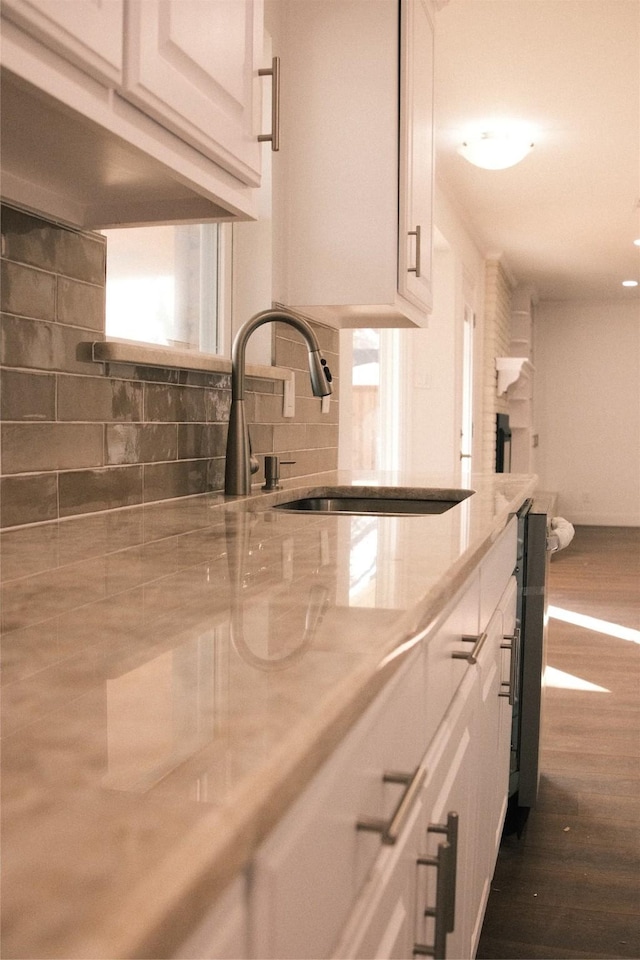 room details with dark wood-type flooring, sink, white cabinetry, and tasteful backsplash