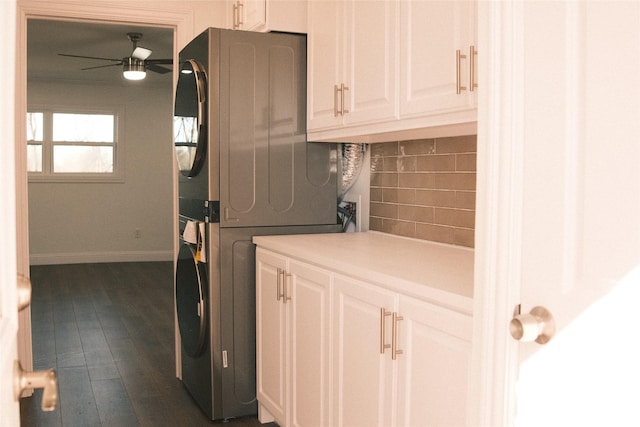 laundry room featuring ceiling fan, dark wood-type flooring, cabinets, and stacked washer and dryer