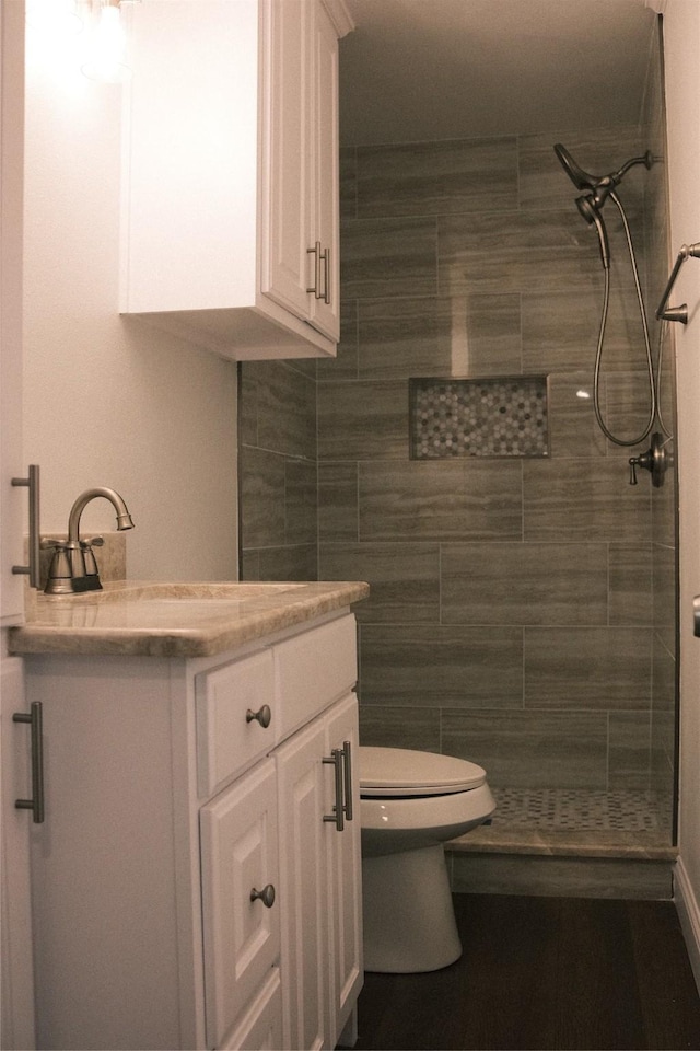 bathroom with toilet, vanity, and tiled shower