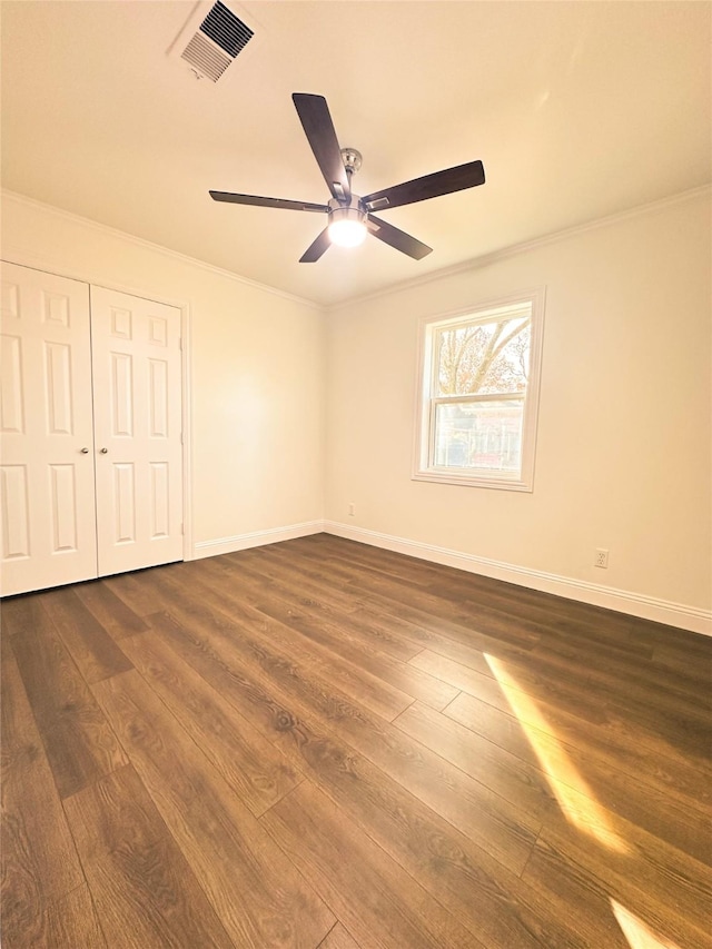 unfurnished bedroom with ornamental molding, a closet, ceiling fan, and dark hardwood / wood-style flooring