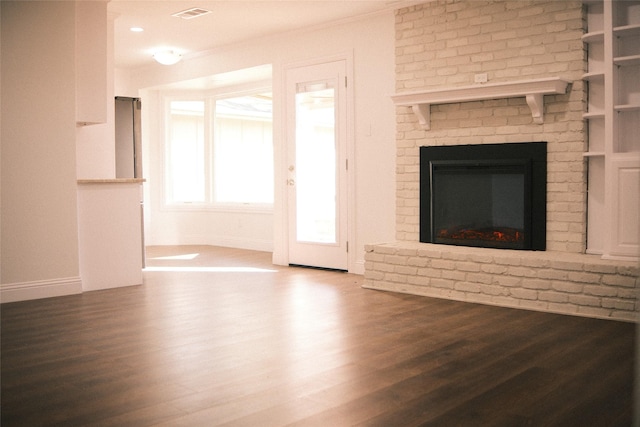 unfurnished living room with hardwood / wood-style floors, a brick fireplace, and ornamental molding