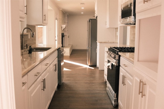 kitchen with appliances with stainless steel finishes, white cabinetry, tasteful backsplash, sink, and dark hardwood / wood-style floors