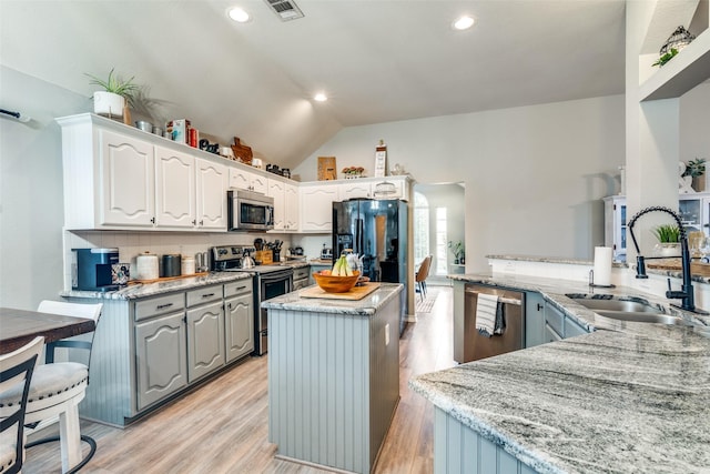 kitchen with kitchen peninsula, appliances with stainless steel finishes, backsplash, sink, and white cabinets