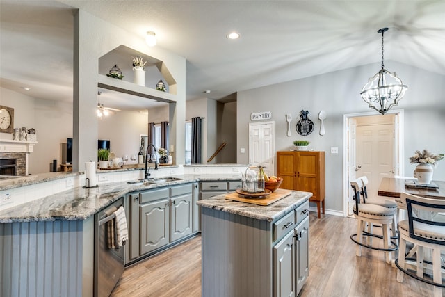 kitchen with kitchen peninsula, sink, a fireplace, gray cabinets, and a kitchen island