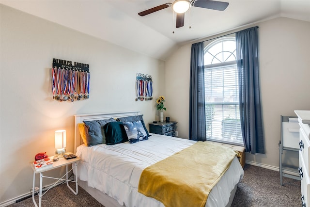 carpeted bedroom with multiple windows, ceiling fan, and vaulted ceiling