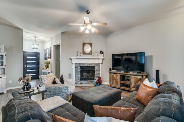 living room with a stone fireplace, ceiling fan, and hardwood / wood-style floors